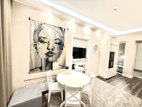 A modern interior featuring a circular table, chairs, and a wall hanging of a woman's face.