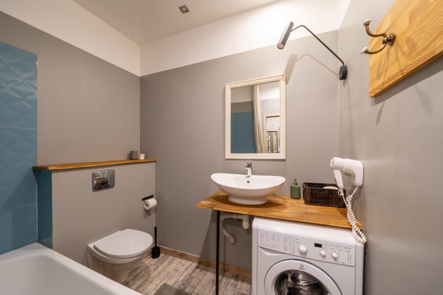 Modern bathroom with a sink, washing machine, and neutral-colored walls.