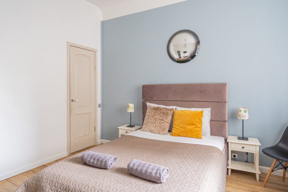 Cozy bedroom with a grey wall, double bed, and decorative pillows.