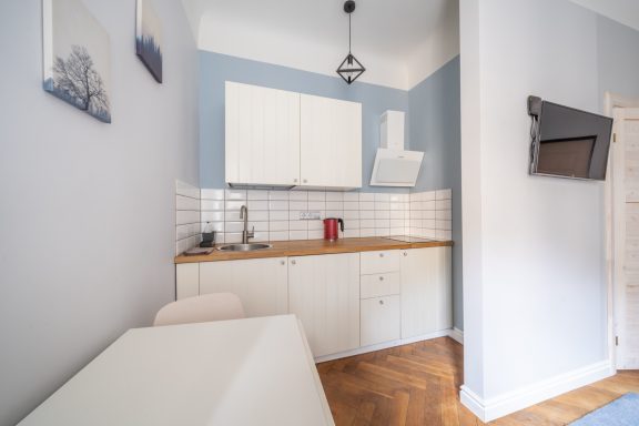 Small modern kitchen with white cabinetry, wooden countertop, and light blue walls.