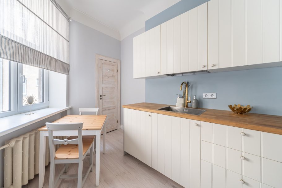 Bright kitchen with white cabinets, wooden countertop, a table, and chairs by the window.