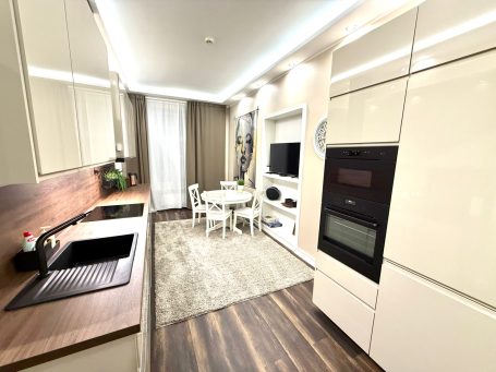 Modern kitchen with white cabinets, a dining table, and a sleek design.