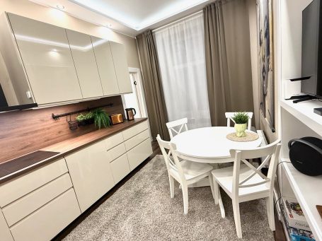 Modern kitchen with white cabinetry, a round dining table, and light curtains.