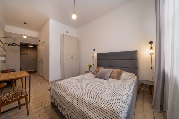 Cozy bedroom with a gray bed, wooden table, and light-colored walls.