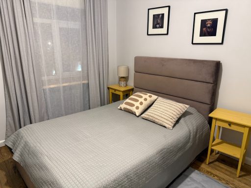 Cozy bedroom with a bed, two yellow nightstands, and light gray curtains.