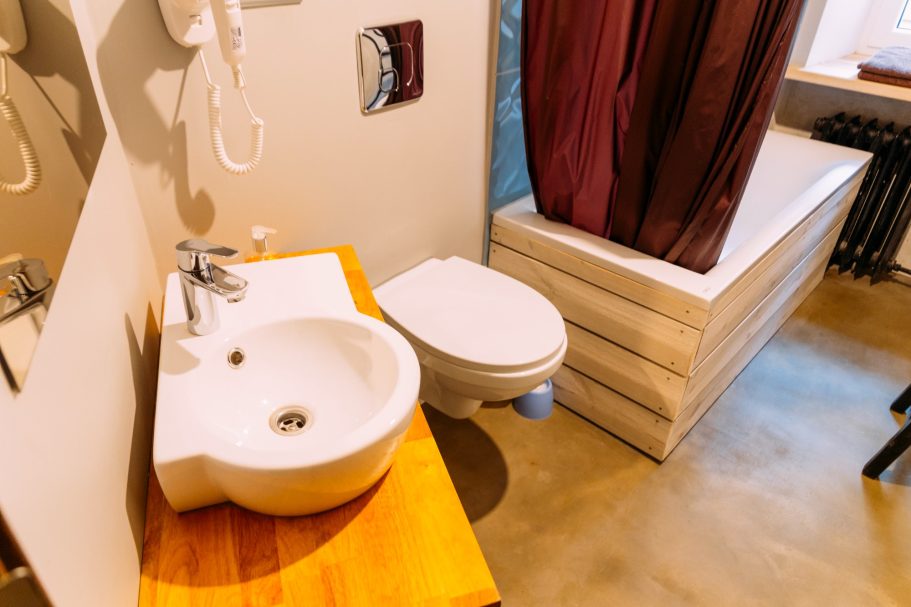 Modern bathroom featuring a sink, toilet, and wooden countertop.