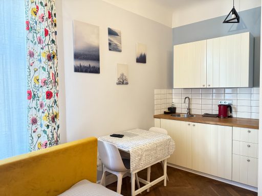 Cozy kitchen area with white cabinets, a small table, and colorful floral curtains.
