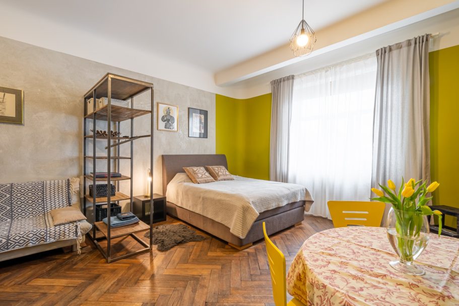 Cozy bedroom with a bed, yellow walls, and a table with tulips.