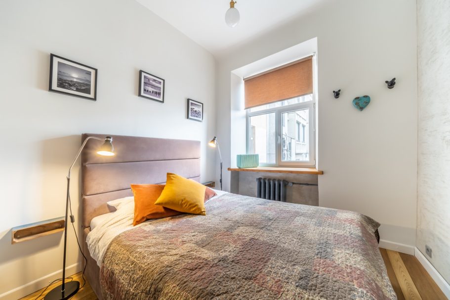 Cozy bedroom with a quilted bedspread, decorative pillows, and framed photos on the walls.