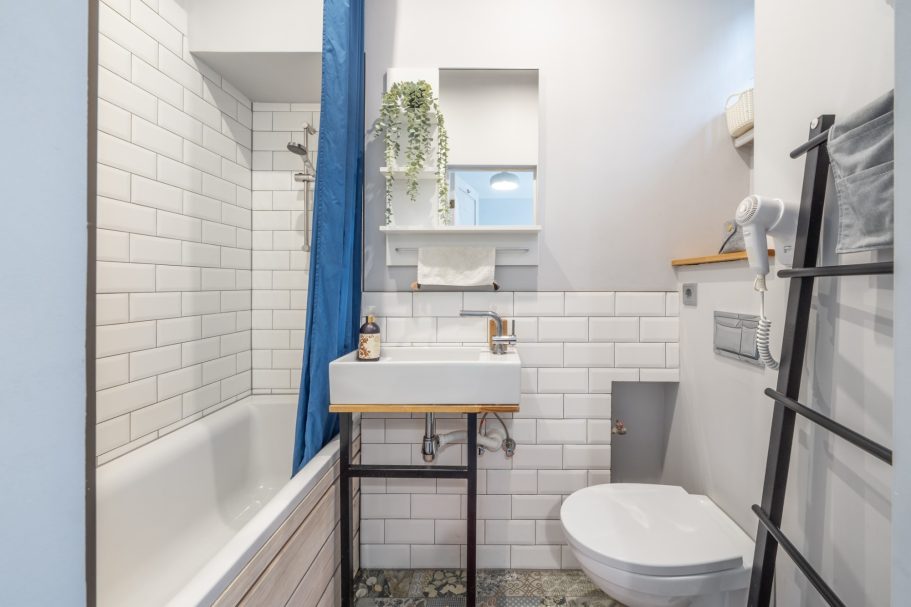 Modern bathroom featuring a bathtub, basin, toilet, and large window with natural light.