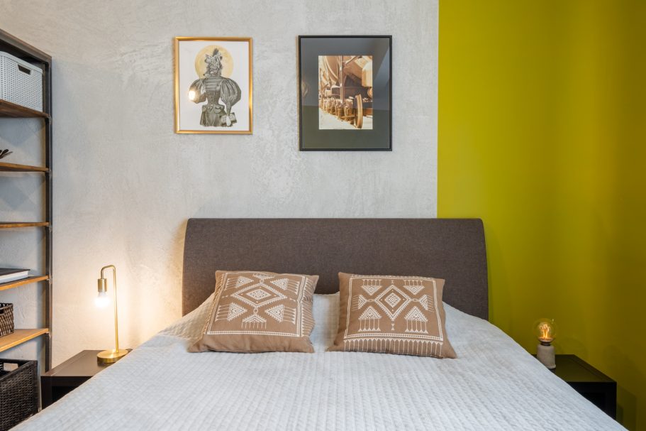 Cozy bedroom featuring a bed with decorative pillows, wall art, and a green accent wall.