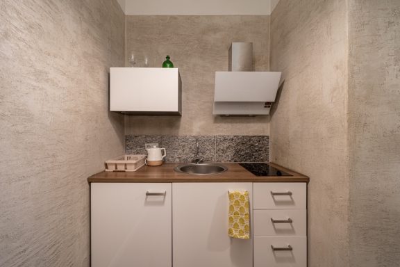 Modern kitchen with gray walls, wood countertop, and minimalistic white cabinets.