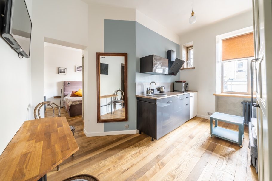 Modern kitchen with wooden flooring, a small dining table, and a mirror.