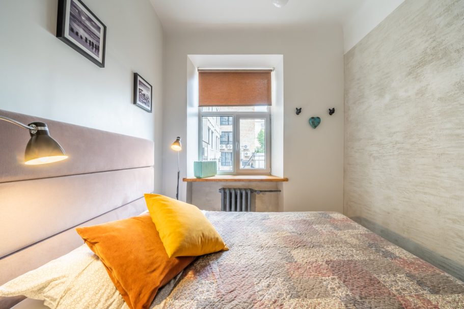 Cozy bedroom with a bed, colorful pillows, and a window letting in natural light.
