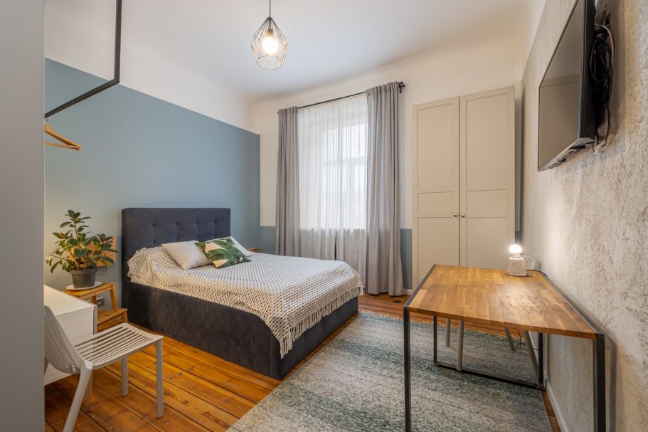 Cozy bedroom with a double bed, desk, and natural light from a window.