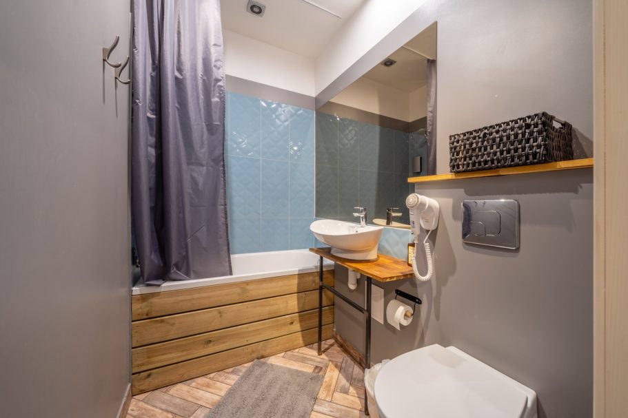 Small modern bathroom with a bathtub, sink, and wooden accents.