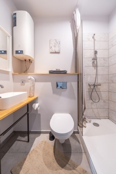 Modern bathroom featuring a shower, toilet, sink, and wooden accents.