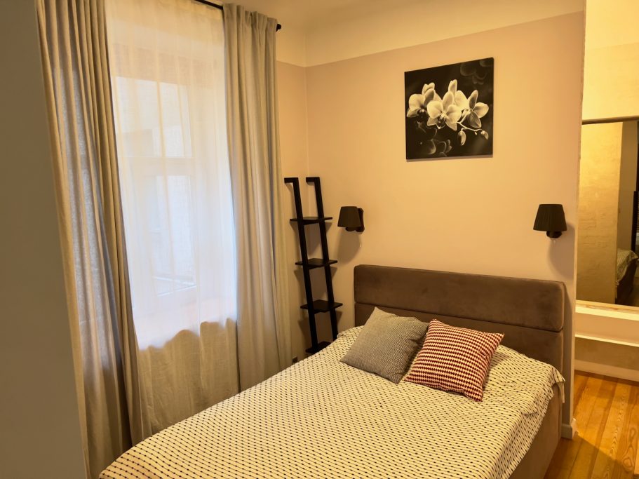 A cozy bedroom with a bed, soft lighting, and decorative wall art.