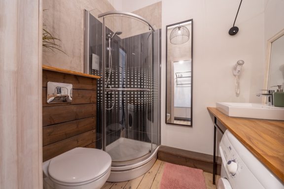 Modern bathroom featuring a shower, toilet, sink, and wooden accents.